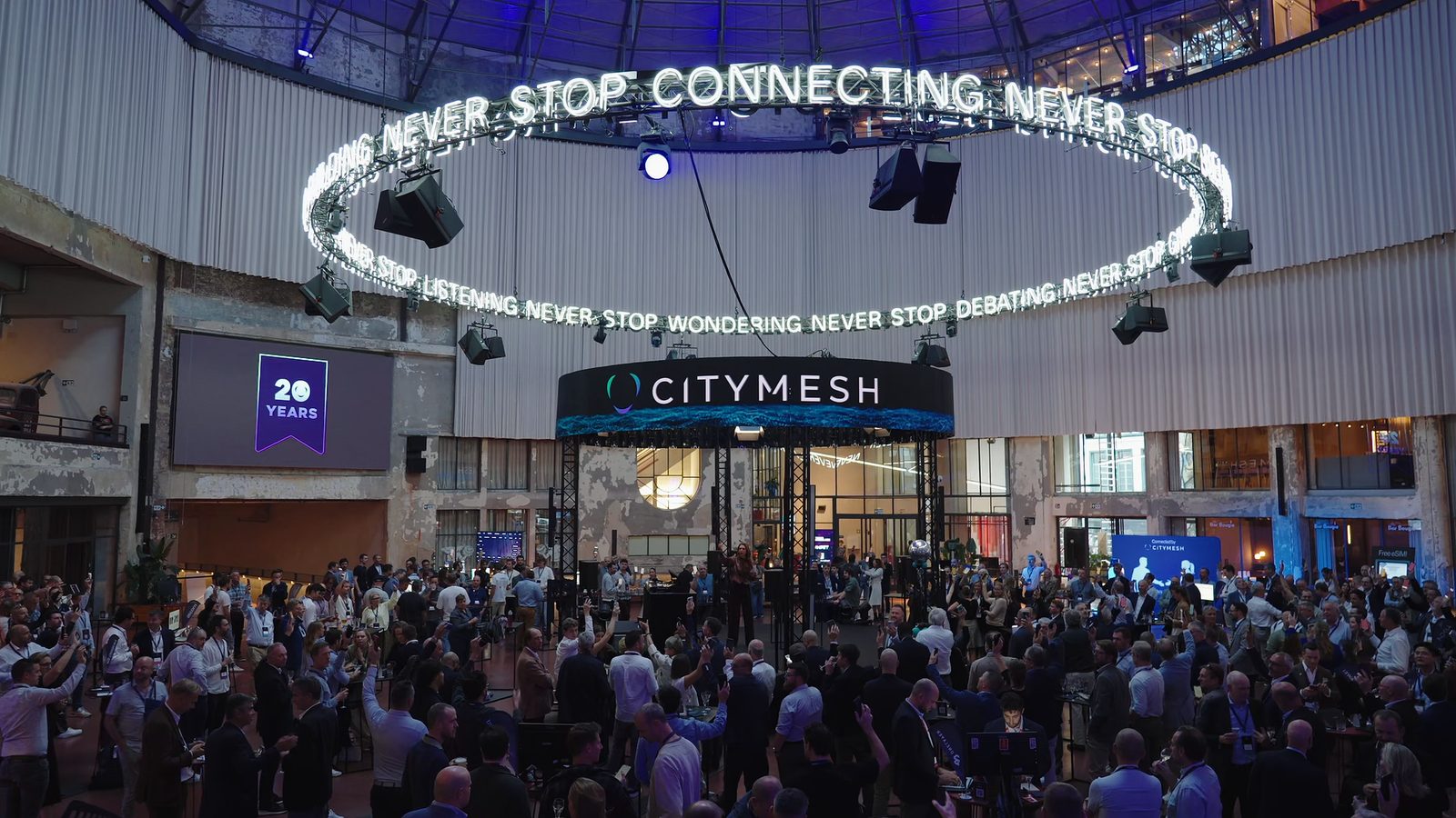The round Wintercircus arena during Citymesh 20Y, with the CITYMESH stage and the 'Never stop connecting' light ring above a packed crowd